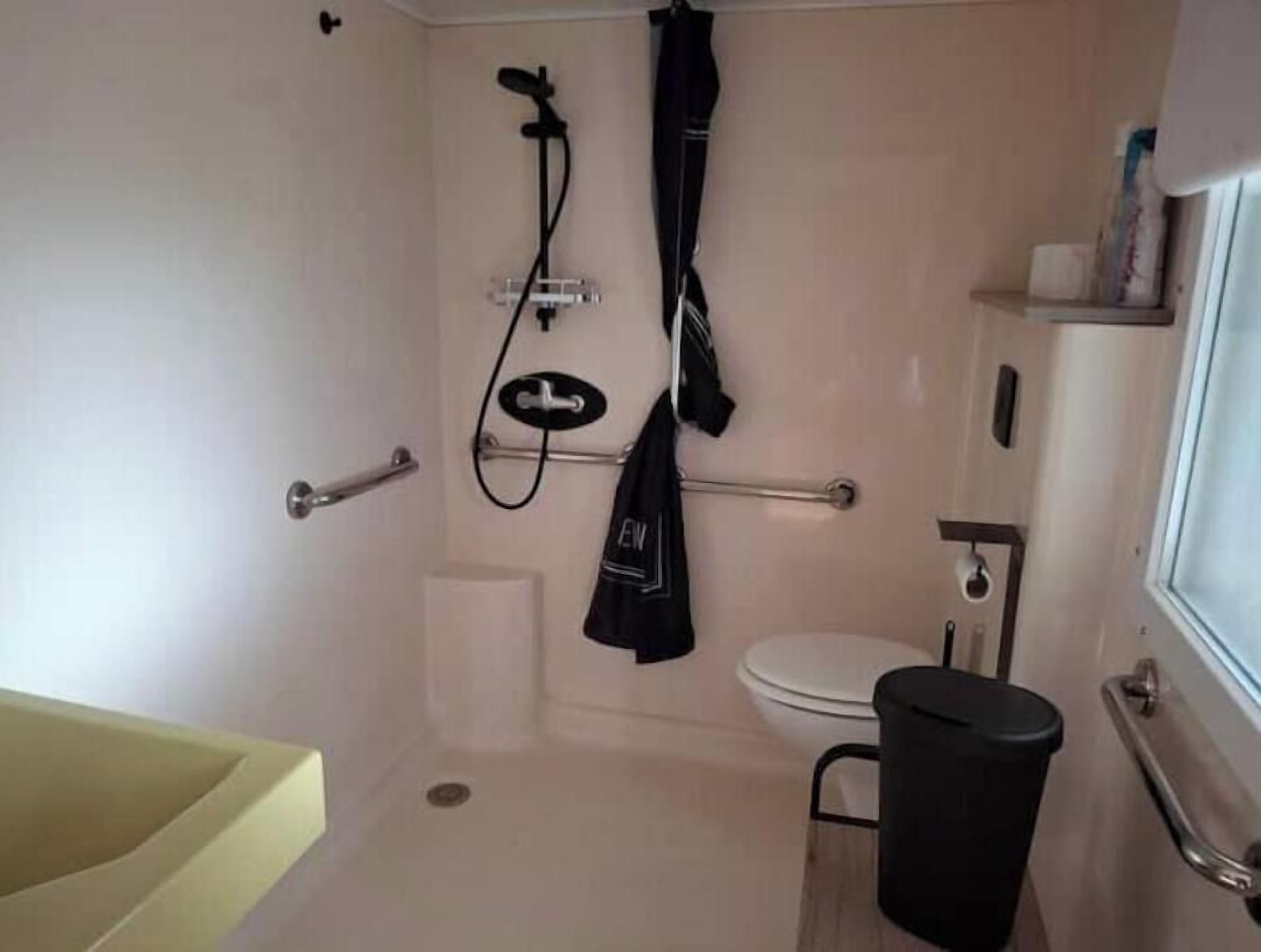 Pieni kylpyhuone, jossa on suihku, wc ja roskakori.