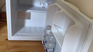 Un refrigerador abierto con un manual, una botella de agua y un cable de alimentación conectado.