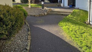 Zona residencial con un camino pavimentado, un árbol y casas modernas.