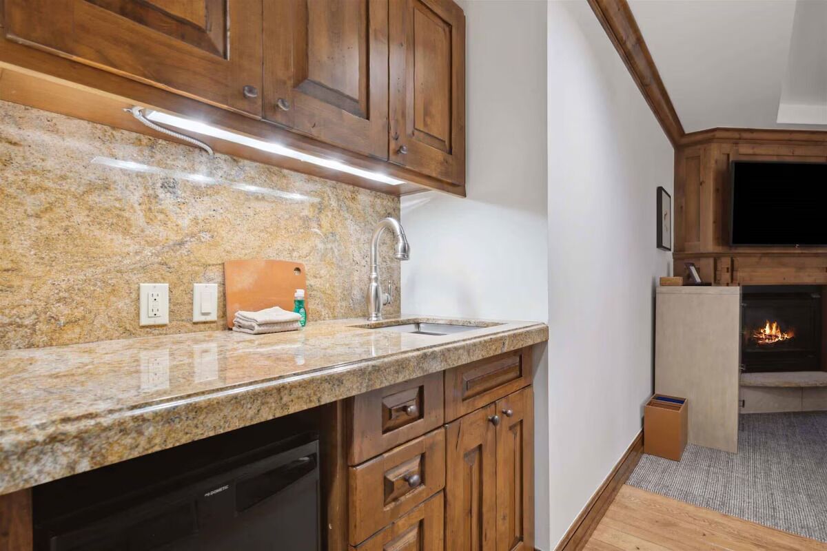 A kitchen with granite countertops, wooden cabinets, a dishwasher, and a fireplace.