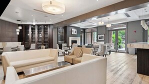 En modern hotellobby med soffor, en öppen spis och utsikt över grönområden.