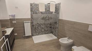 A modern bathroom with a shower, toilet, bidet, and a sink.