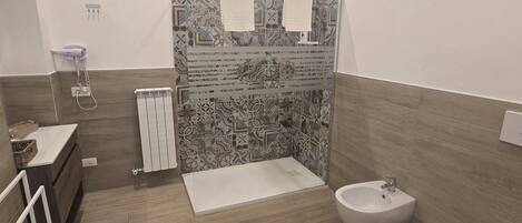 A modern bathroom with a shower, toilet, bidet, and a sink.