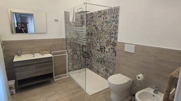 Une salle de bain équipée d’une douche, de toilettes, d’un bidet et d’un lavabo.