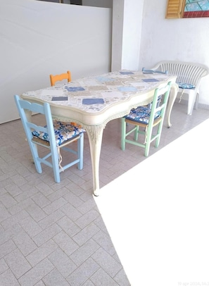 A dining table with chairs, a tiled floor, and a wall with a picture.