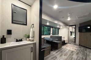 A modern bathroom with a sink, mirror, and towel rack.