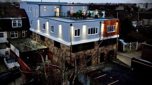 A multi-story residential building with a rooftop terrace, multiple windows, and a visible garage.