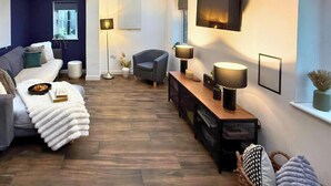 Ein modernes Wohnzimmer mit einer Couch, einem Sessel und einem an der Wand befestigten Fernseher.