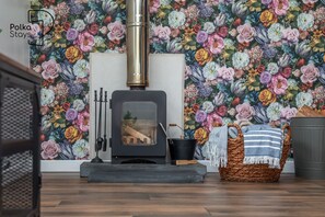 A room with a wood-burning stove, a woven basket, and a striped throw. - Hen Stablau Spacious Modern Family Retreat in North Wales Sleeps 8 (Maerdy)