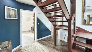 Eine Treppe mit Holzgeländern, einer blauen Wand und einer weißen Tür zu einem anderen Raum.
