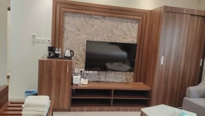 A modern living room with a flat-screen TV, wooden entertainment unit, and a sofa. - qamar albahr (Al Khobar)