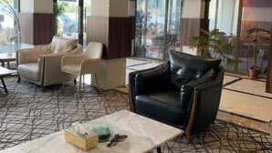 A lobby with leather sofas, a marble coffee table, and large windows with a view of the outside. - qamar albahr (Al Khobar)