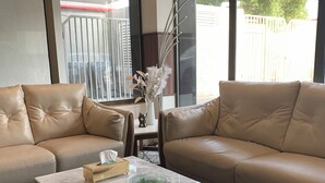 A modern living room with leather sofas, a glass coffee table, and a view of the outdoors. - qamar albahr (Al Khobar)