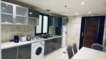 A compact kitchen with a washing machine, a dining table, and chairs.