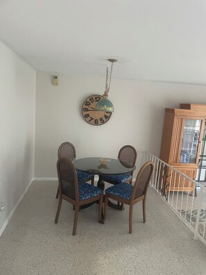 A dining area with a round table, four chairs, a wall clock, and a wooden cabinet. - Poolside Cozy 2 bedroom pet friendly perfect getaway (Port Charlotte)