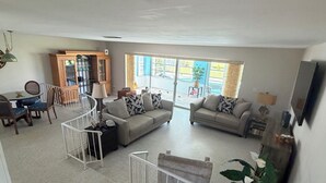 A spacious living area with a dining table, two sofas, a cabinet, and a large window. - Poolside Cozy 2 bedroom pet friendly perfect getaway (Port Charlotte)