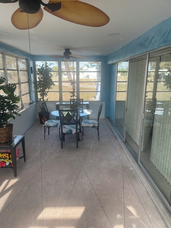A sunroom with a dining table, chairs, a ceiling fan, and large windows. - Poolside Cozy 2 bedroom pet friendly perfect getaway (Port Charlotte)