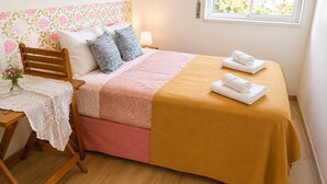 A neatly made bed with a pink and yellow bedspread, two pillows, and two rolled towels on the side. - Spacious Lisbon Apartment With 4 Bedrooms (Lisbon)