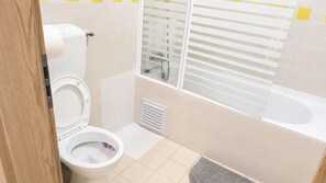 Een badkamer met toilet, douche en bad.