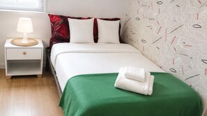 A neatly made bed with a green bedspread and white pillows, a bedside lamp, and a patterned wall. - Spacious Lisbon Apartment With 4 Bedrooms (Lisbon)