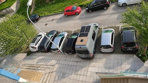 A parking area with multiple cars, a solar panel on a vehicle, and a staircase leading to an upper level. - Spacious Lisbon Apartment With 4 Bedrooms (Lisbon)