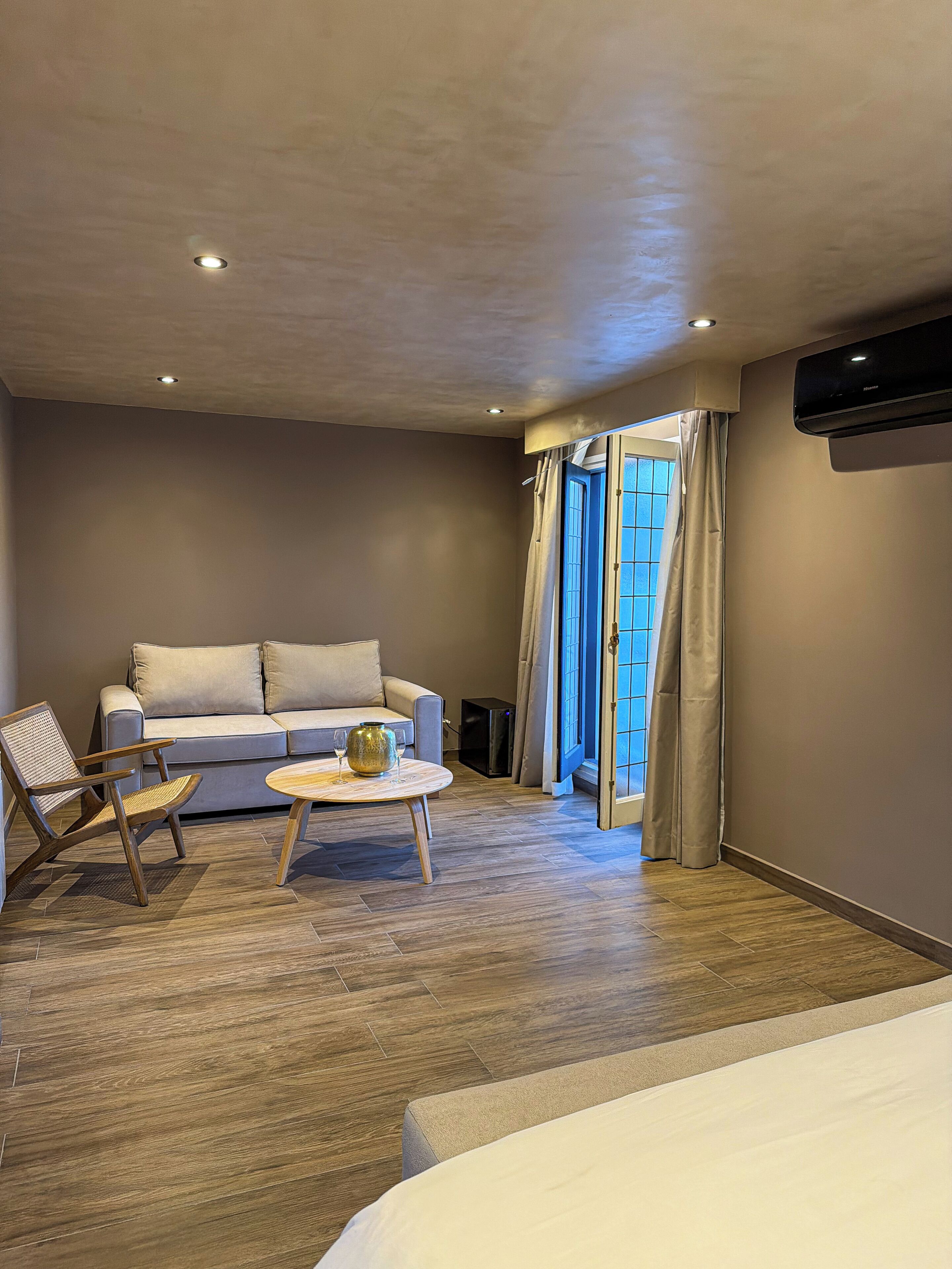 Una habitación de hotel moderna con sofá, sillón, mesa de centro y cama.