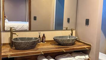 Une salle de bain avec deux vasques en pierre, un meuble-lavabo en bois et un miroir.