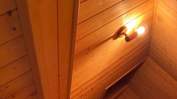 Un intérieur en bois, avec un escalier en bois, un mur en bois et un luminaire.