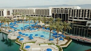 A hotel with a large pool area, multiple lounge chairs, and palm trees. - StageCoach Weekend Stay – Luxury 2BR Villa - Sleeps 8! (Palm Desert)
