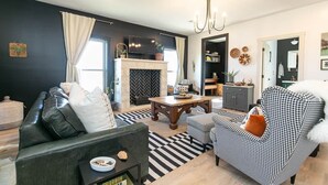 Una sala de estar moderna con chimenea, sofá de estampado blanco y negro y una araña.
