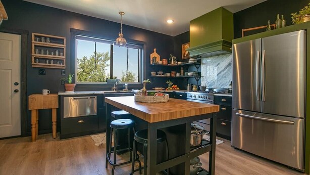 Una cocina moderna con una isla central, electrodomésticos de acero inoxidable y vistas al exterior.