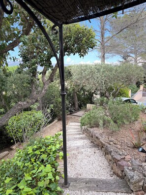 A garden pathway with a pergola structure, surrounded by various plants and trees. - Villa with pool & putting green - Saint-Raphaël - peaceful setting (Saint-Raphaël)