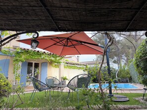 A covered patio with outdoor furniture, a swimming pool, and a house with blue shutters. - Villa with pool & putting green - Saint-Raphaël - peaceful setting (Saint-Raphaël)