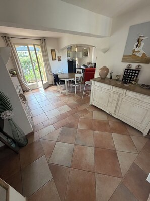 A spacious kitchen with a dining area, a large window, and a view of greenery outside. - Villa with pool & putting green - Saint-Raphaël - peaceful setting (Saint-Raphaël)