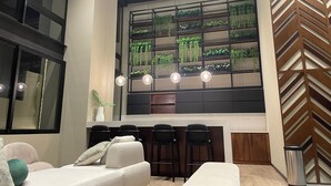 Ein modernes Interieur mit einer Couch, Barhocker, einer Hängeleuchte und einer Wandpflanzen-Anlage.
