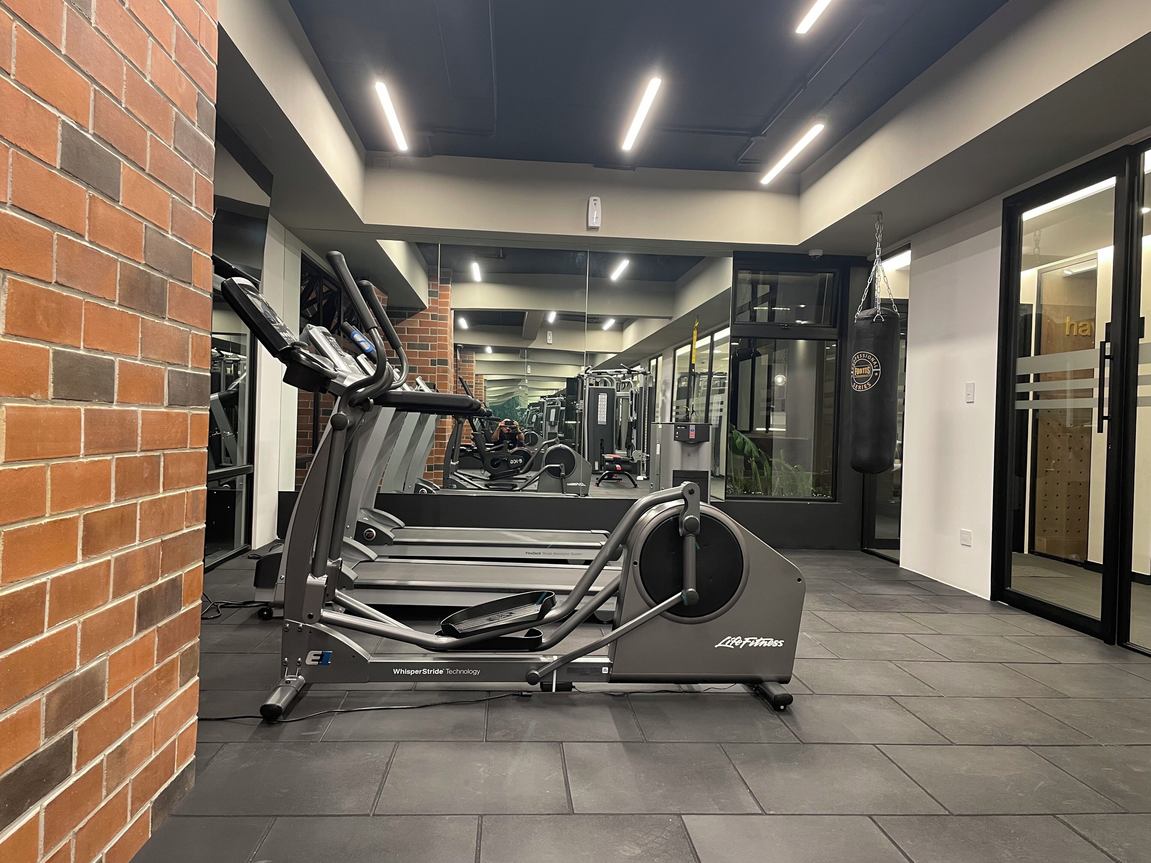 Ein Fitnessstudio mit Laufbändern, Kraftgeräten und einer Spiegelwand.