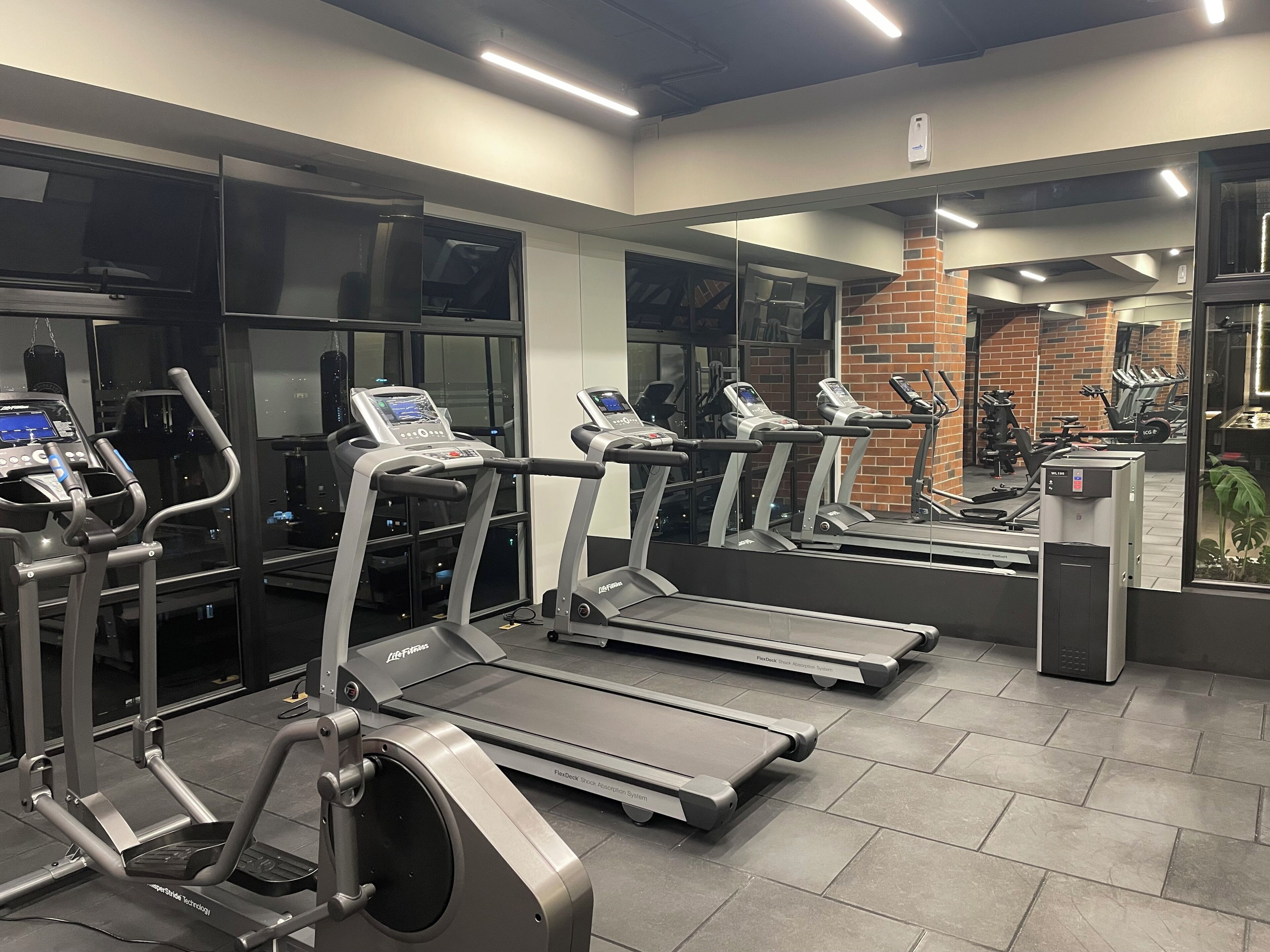 Un gimnasio con cintas de correr, elípticas y máquinas de pesas.
