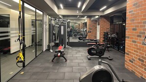Ein Fitnessraum mit Trainingsgeräten, einem Spiegel und einer Ziegelwand.