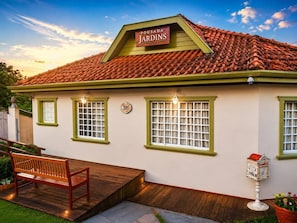 A building with a sign reading 'POUSADA JARDINS,' a wooden bench, and a mailbox. - Pousada Jardins (Campos do Jordão)