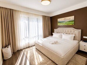 Ein Hotelzimmer mit einem großen Bett, einem Nachttisch, einem Bild an der Wand und einem Fenster mit Vorhängen.