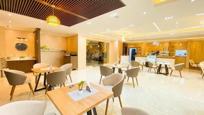 Eine Hotelhalle mit Rezeption, Sitzgelegenheiten und Blick in den Speisesaal.
