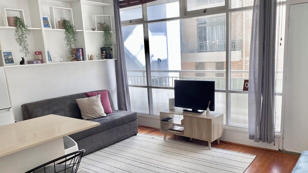 A modern living room with a sofa, TV, and dining area. - The Bondi Beach Escape (Sydney)