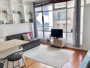 Una sala de estar moderna con un sofá, televisión y comedor.