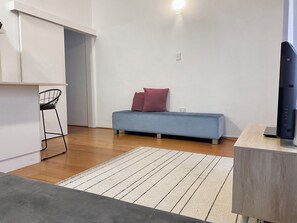 Un espacio habitable moderno con sofá, sillón, televisor de pantalla plana y piso de madera.