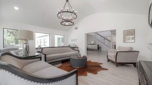 Uma sala de estar moderna com um lustre, um sofá, uma mesa de centro e um tapete de couro bovino.
