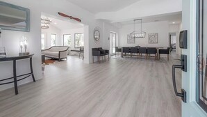 Uma sala ampla com uma mesa de jantar, cadeiras, um sofá e um espelho grande.