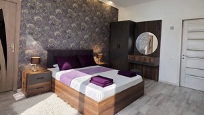 A bedroom with a bed, nightstands, a mirror, and a wardrobe.