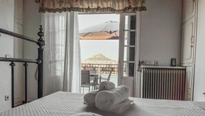 A bedroom with a bed, a radiator, a window with curtains, and a view of a building outside. - Unique sunlit house overlooking the Acropolis (Athina)