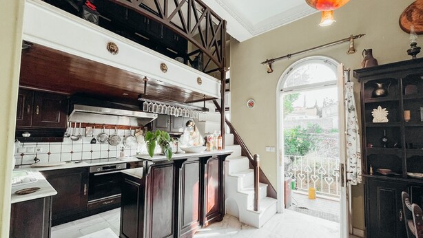 A kitchen with dark wooden cabinets, a white countertop, and a view to the outside. - Unique sunlit house overlooking the Acropolis (Athina)
