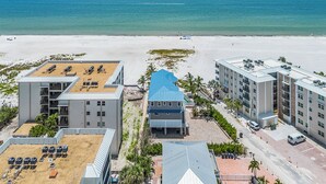 A beachfront hotel with multiple buildings, a sandy beach, and the ocean in the background. - Island Girl vacation Home (Fort Myers Beach)